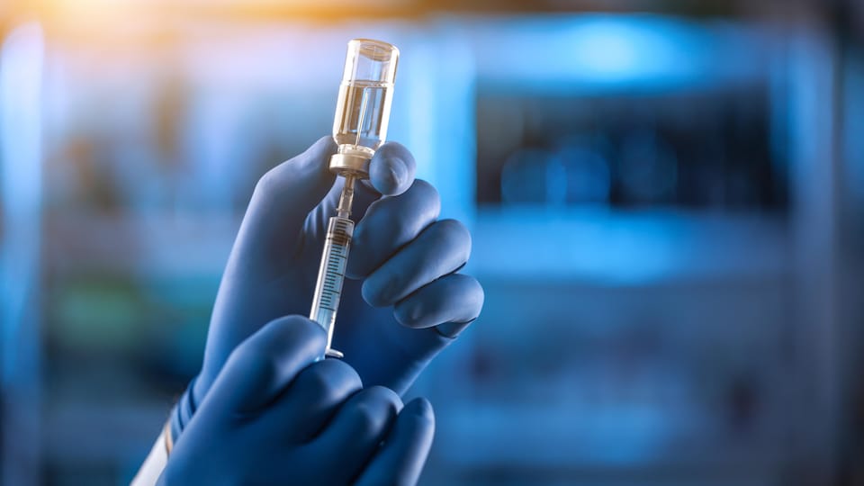Un chercheur tient une dose de vaccin dans ses mains.