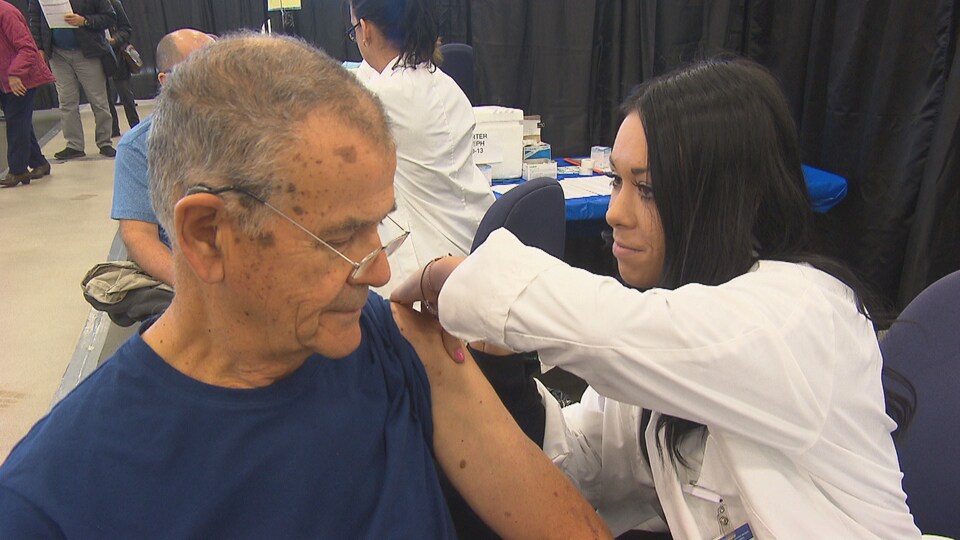 Une infirmière administre à un homme un vaccin contre le grippe.