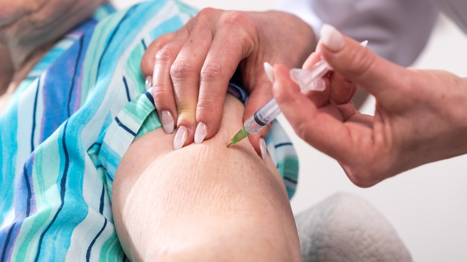 A nurse vaccinates an elderly person.