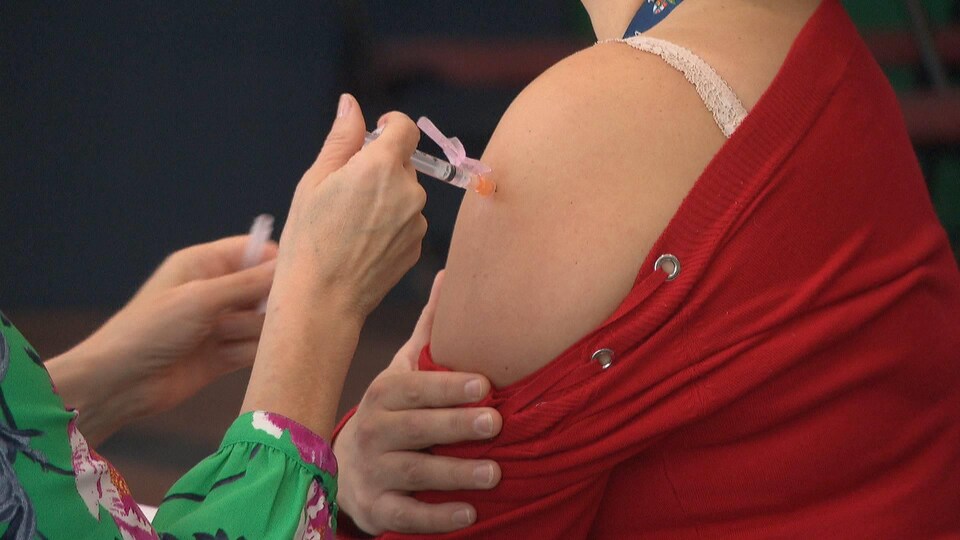 Aiguille dans le bras d'une femme qui se fait vacciner.