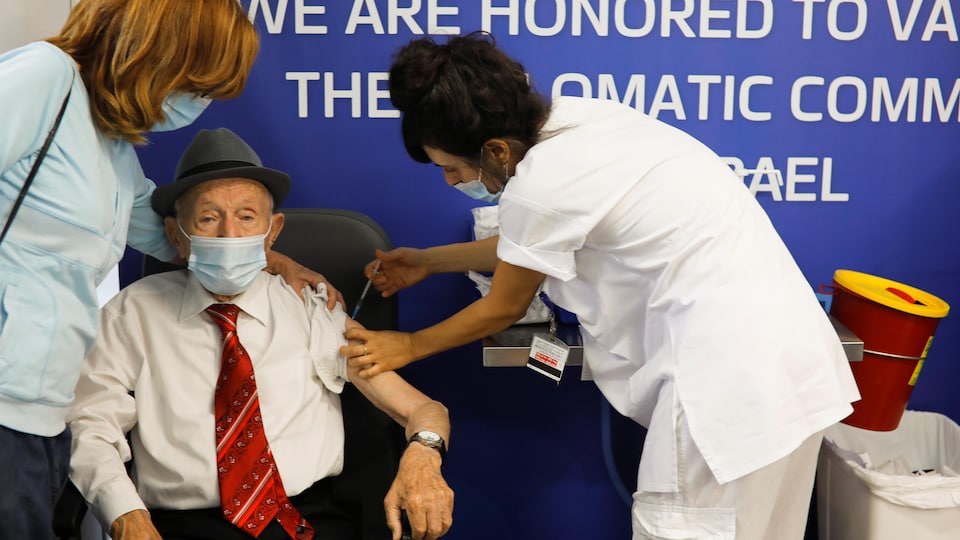 Une infirmière injecte un vaccin dans le bras d'un homme âgé.
