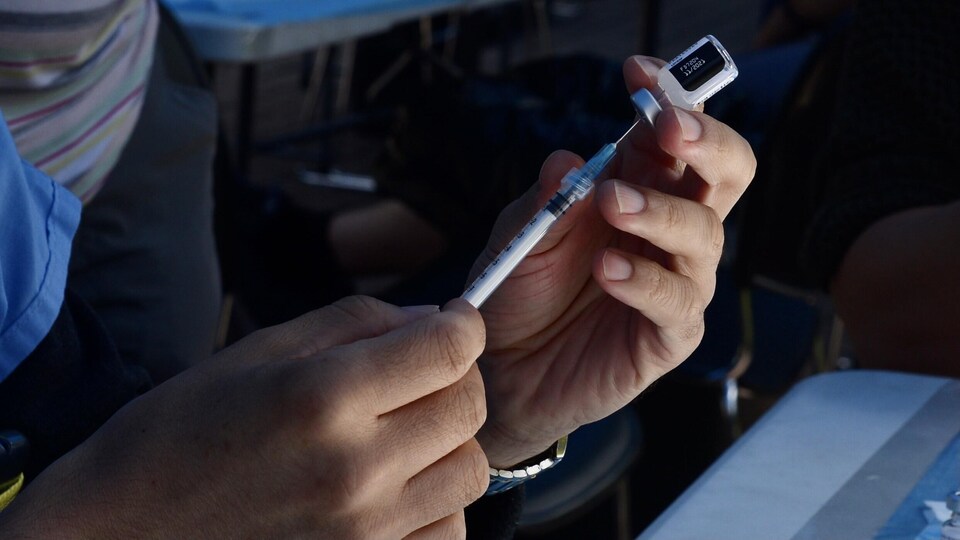 Une femme remplit une seringue à partir d'une fiole de vaccin.