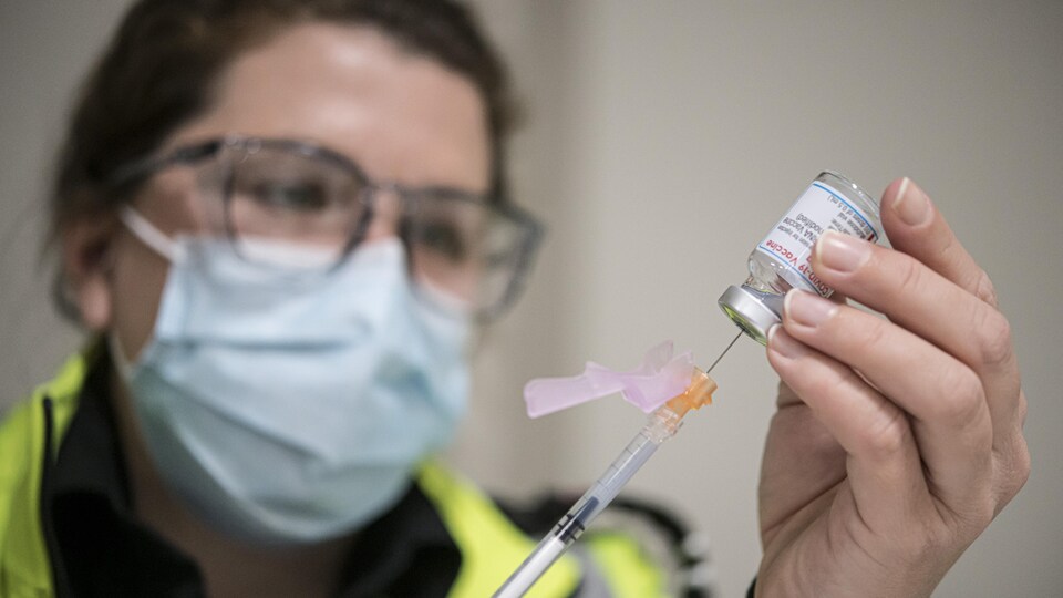 Une femme portant un masque de protection prépare une injection.
