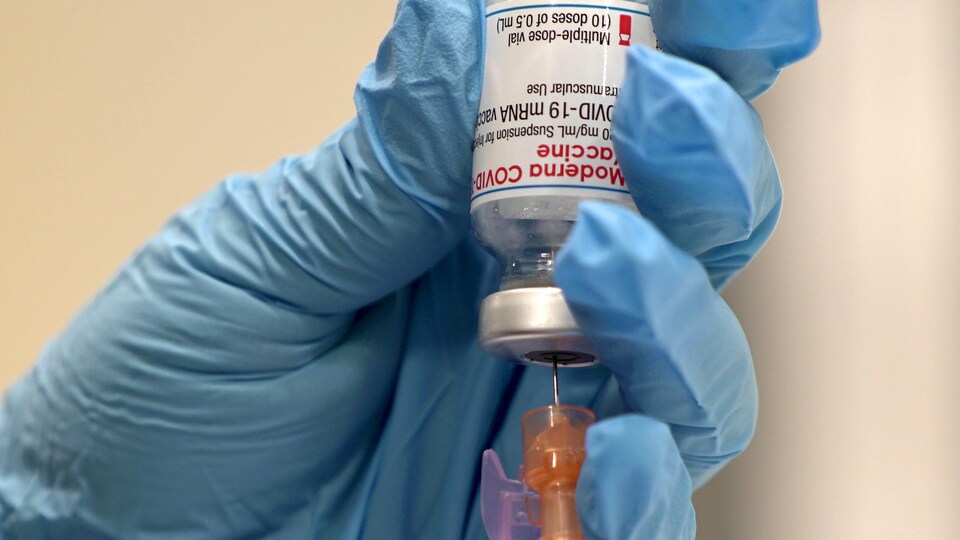 Une aiguille introduite dans une fiole du vaccin de Moderna.