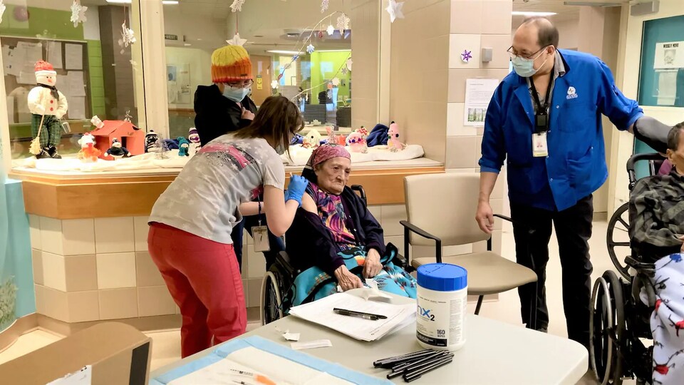 Une infirmière administre un vaccin à une femme âgée.