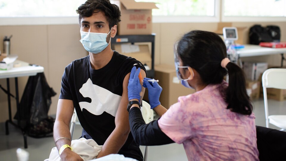 Une infirmière vaccine un adolescent.