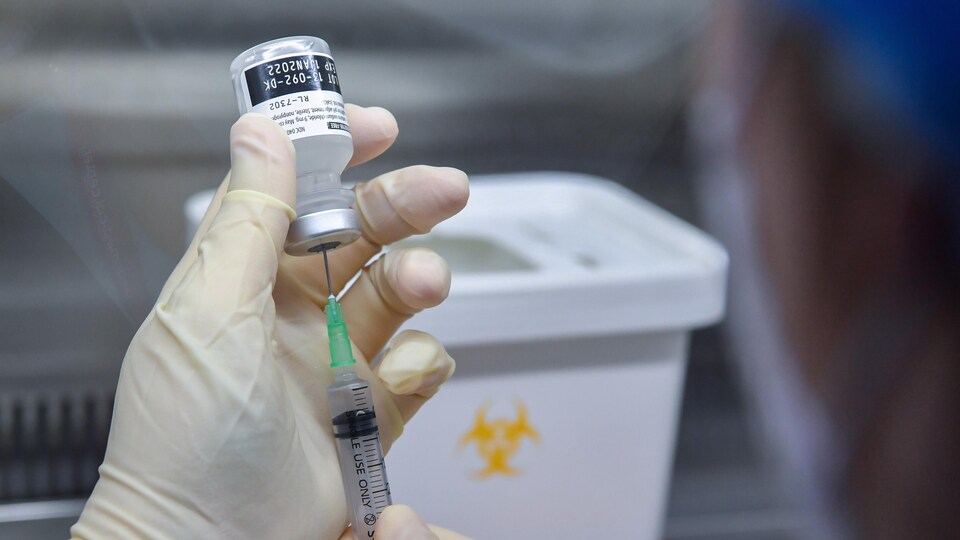 Une infirmière extrait à l’aide d’une seringue le vaccin contre la COVID-19 de Pfizer BioNTech.