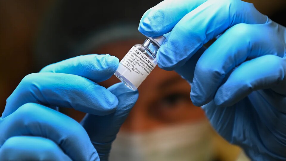 Une personne manipule une fiole de vaccin.