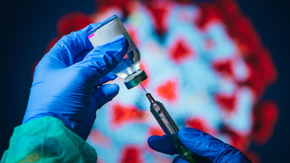 Des mains gantées remplissent une seringue à partir d'une bouteille de vaccin, avec une représentation du coronavirus en arrière-plan.
