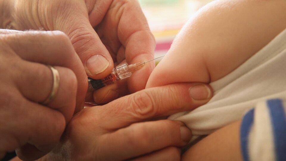 Gros plan sur un pédiatre qui vaccine un bébé.