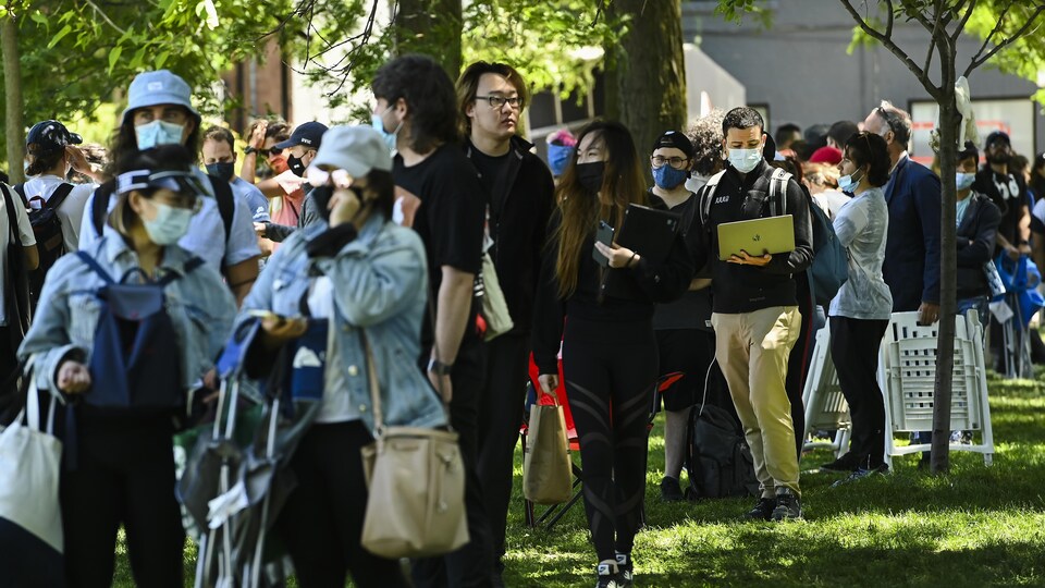 Des milliers de personnes en file dans un parc.