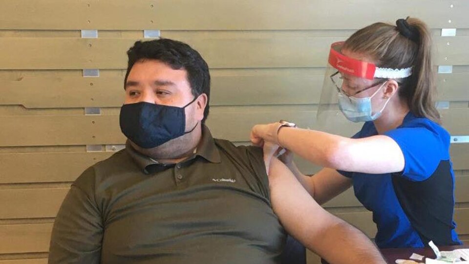 Bryan Mark se fait  vacciner par une infirmière.