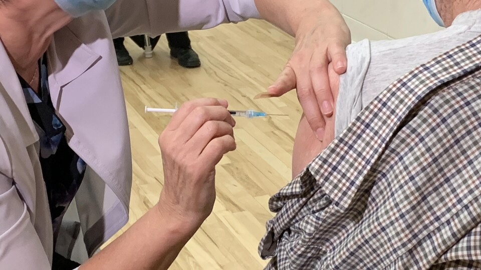 Gros plan sur une femme qui vaccine un homme.