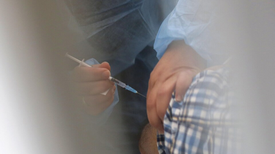 Le bras d'un homme en train de se faire vacciner.