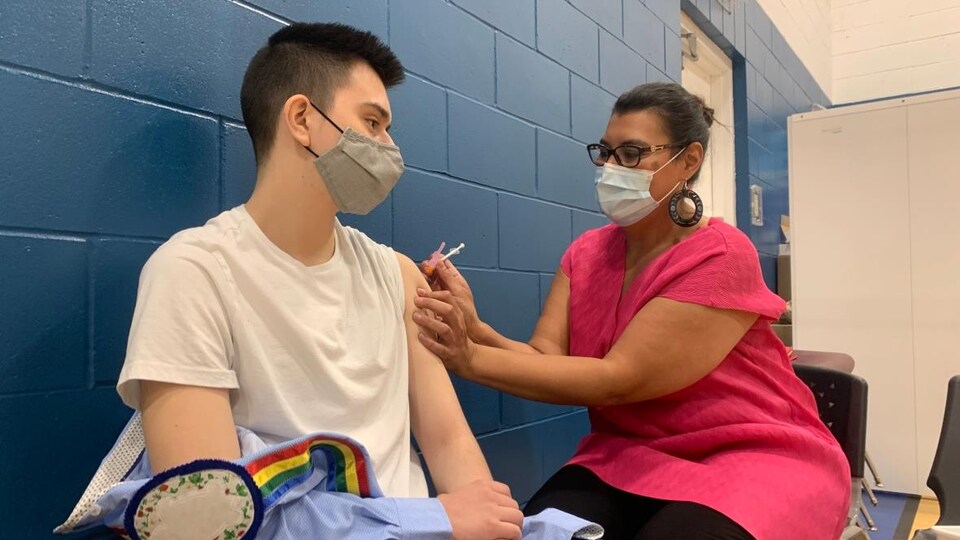 Un jeune homme reçoit un vaccin par un médecin.