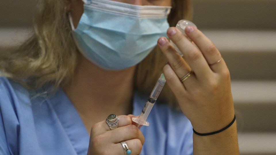 Une préposée insère le vaccin dans une seringue.