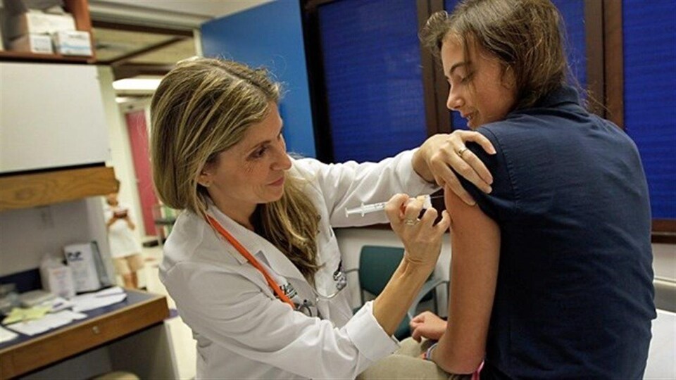 Une infirmière vaccine une jeune fille dans le bras.