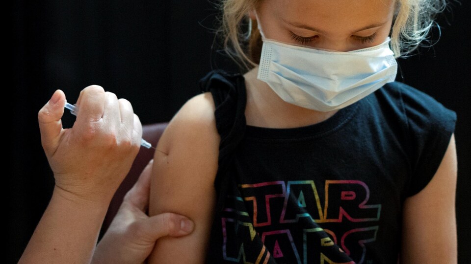 Une petite fille portant un t-shirt de Star Wars reçoit un vaccin.