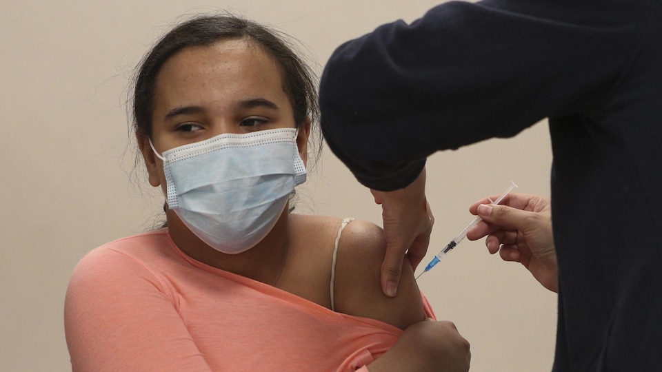 Une jeune fille se fait vacciner sur le bras.