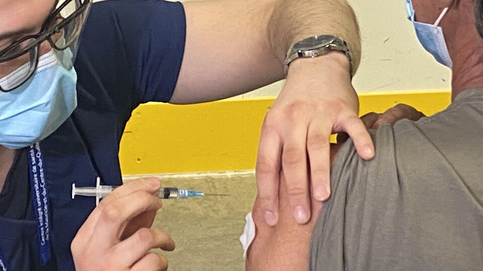 Une personne administre une dose du vaccin d'AstraZeneca.