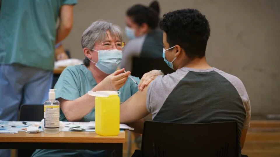 Une professionnelle de la santé injecte un vaccin à un étudiant.