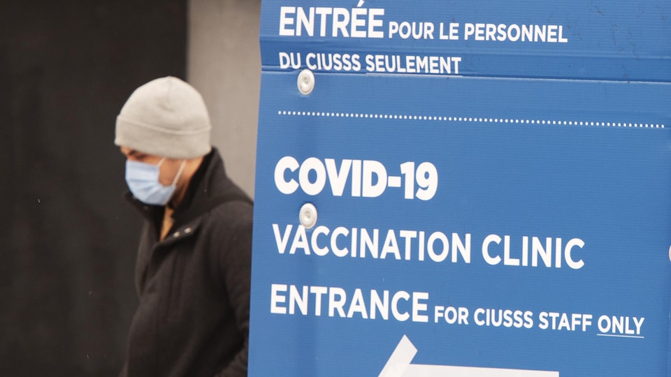 Un homme masqué passe près d'une pancarte annonçant la clinique.