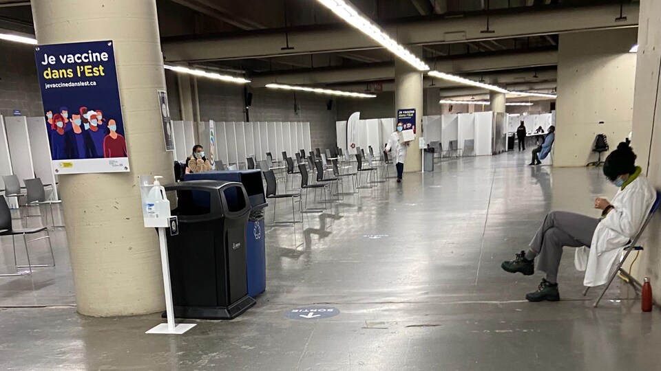Dans les corridors de la clinique de vaccination du stade olympique, des travailleurs de la santé se reposent.