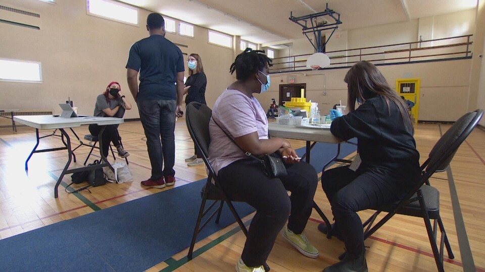 Une femme se fait vacciner dans un gymnase.
