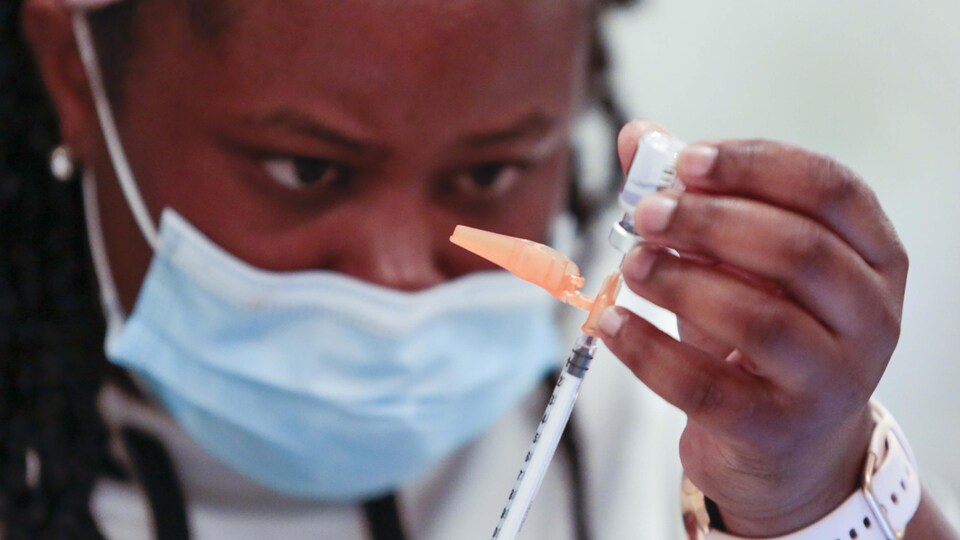 Une infirmière remplit une seringue avec une dose du vaccin.