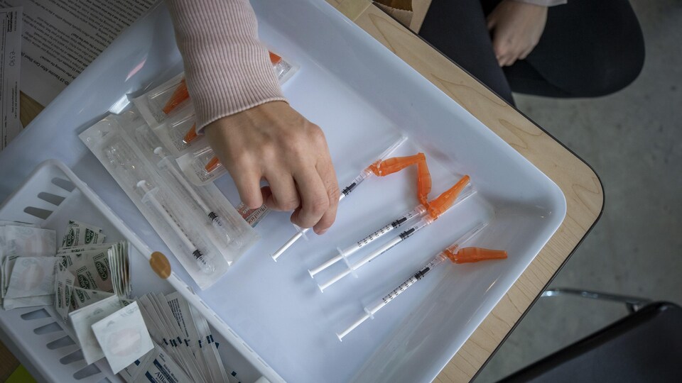 Les cliniques de vaccination contre la COVID-19 emploient de nombreux retraités, qui sont notamment convertis en vaccinateurs. Des aiguilles sur un plateau dans un centre de vaccination.