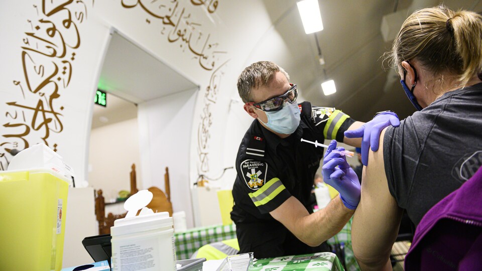 L'ambulancier paramédical Ryan Kingsborough vaccine une femme à la mosquée Nexus de Mississauga.
