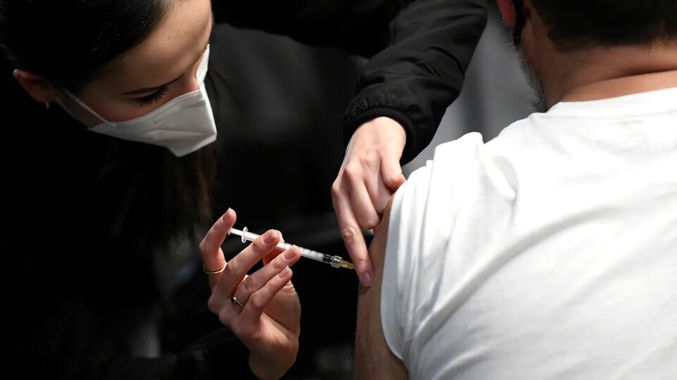 Une personne administre un vaccin à une autre.