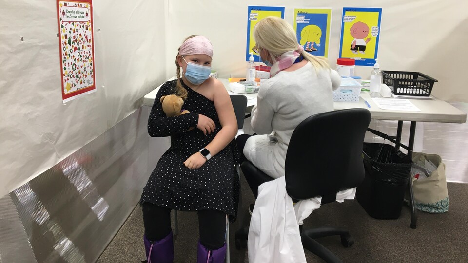 Une fillette armée de sa peluche reçoit son vaccin anti-COVID à la Bâtisse industrielle de Trois-Rivières.