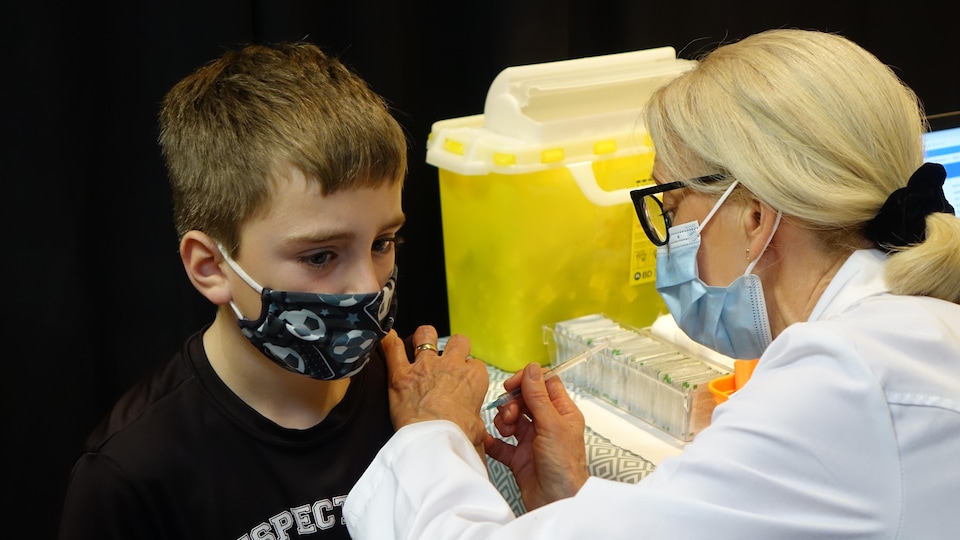 Une infirmière administre un vaccin à un jeune garçon.