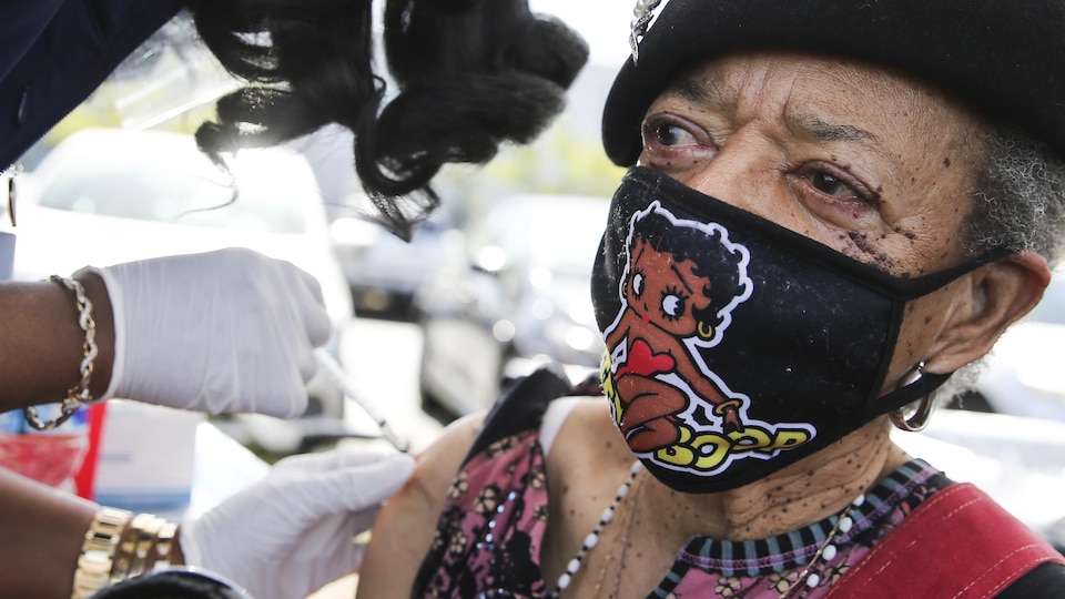 La dame, qui porte un masque avec une image de Betty Boop, reçoit son vaccin sur l'épaule.