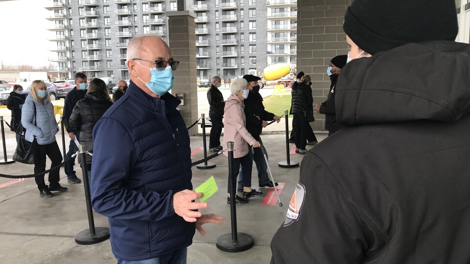 Un homme fait la file avec son coupon pour se faire vacciner à Lévis.
