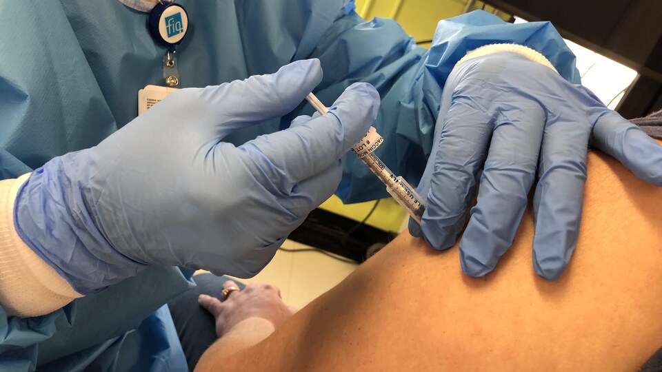 Une seringue injectant une dose de vaccin dans le bras d'une membre de la communauté de Mashteuiatsh. 