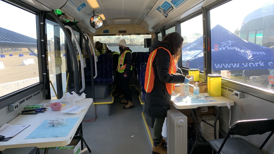 Des personnes dans un autobus aménagé avec des tables de travail.