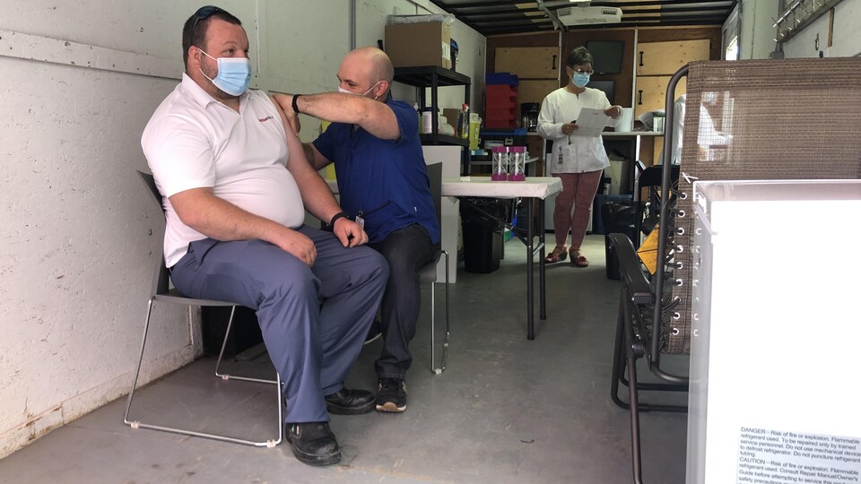 Un homme se fait vacciner contre la COVID-19 dans une clinique mobile.