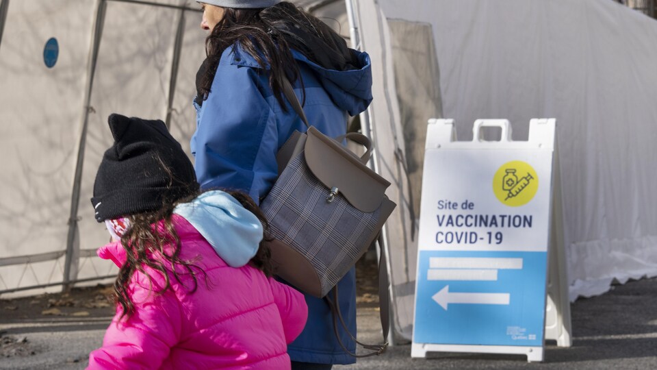 Une femme et un enfant passent devant l'entrée d'une clinique de vaccination contre la COVID-19 à Montréal.