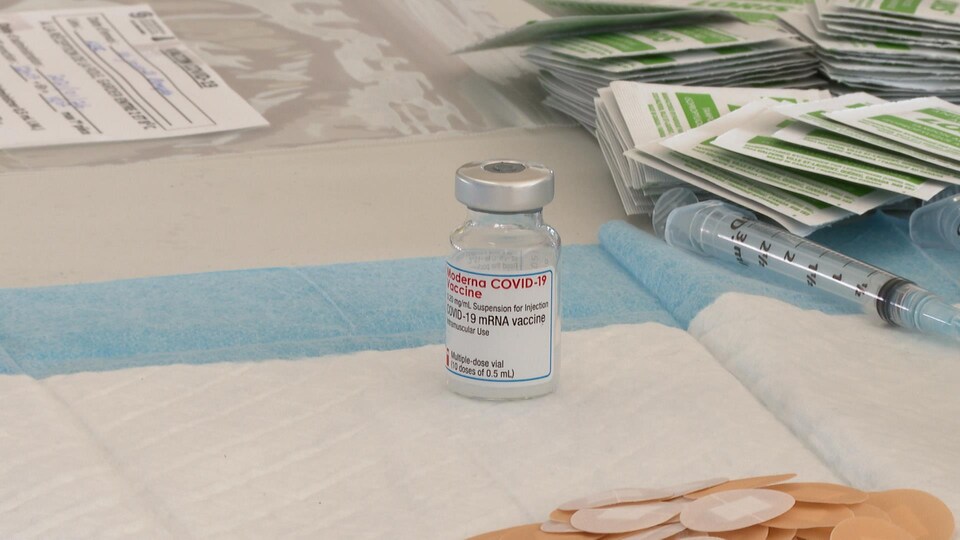 Un flacon du vaccin est déposé sur une table tout près de seringues et de diachylons.