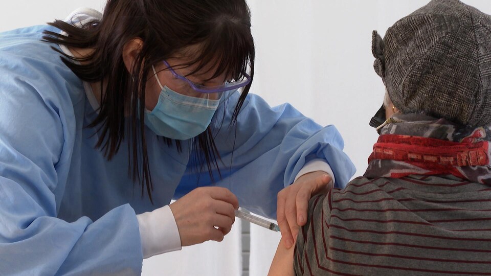 Une femme vaccine une aînée.