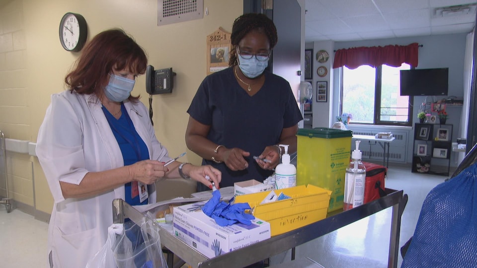 Deux femmes préparent du matériel médical.