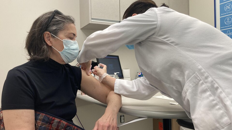 Une dame portant le masque reçoit une dose du vaccin d'AstraZeneca.