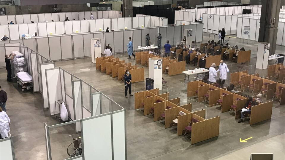 Une vue en plongée montrant les aires d'attente et les cubicules de vaccination dans une immense clinique aménagée dans le Centre de foires ExpoCité.