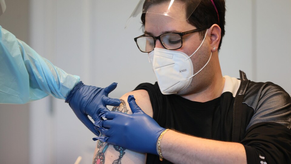 Un homme appuie sur son bras après avoir été vacciné.