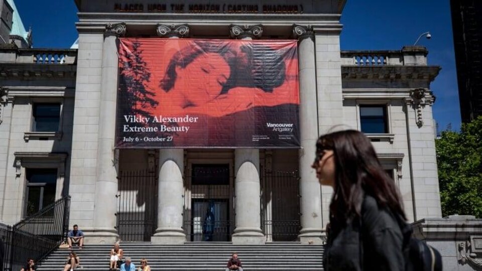 Une femme marche devant le musée des beaux-arts de Vancouver.