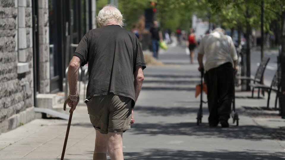 Des aînés marchent sur un trottoir.