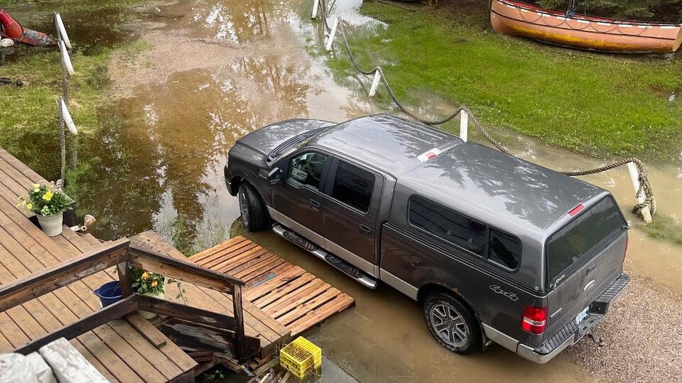 Un terrain et le perron d'une maison inondés par quelques centimètres d'eau.