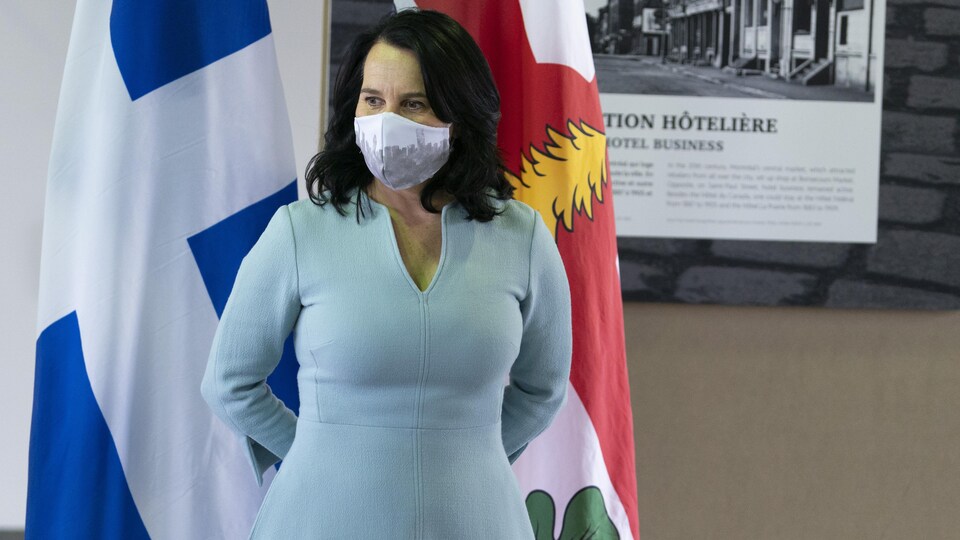Valérie Plante se tient devant les drapeaux du Québec et de Montréal.